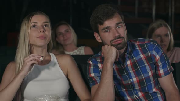 Young People Watching a Boring Movie at the Cinema, One Guy Is Sleeping