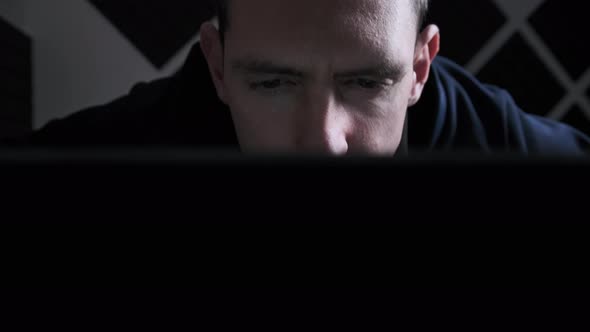 Young Man Looks at a Laptop Monitor Screen in a Dark Room at Home Male Read