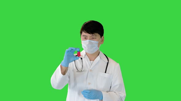 Young Asian Doctor Comparing Two Ampules with Red and Blue Solution on a Green Screen Chroma Key