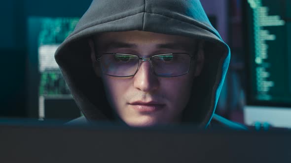 A Hacker in a Hood and Glasses Smirks