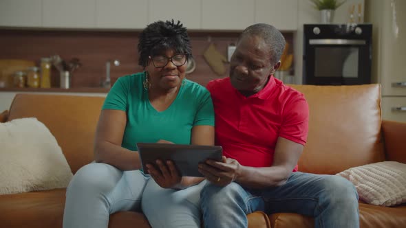 Senior Black Couple Sharing Tablet Pc on Sofa