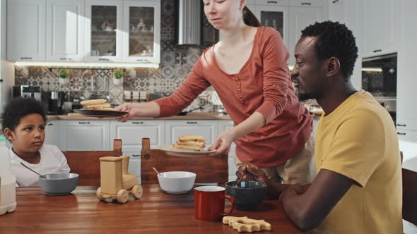 Woman Serving Pancakes to Family