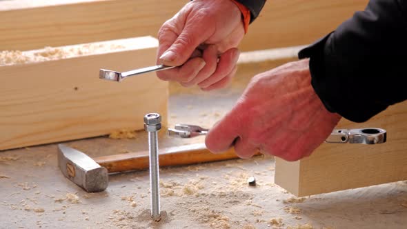 Hands of master twist washer with nut onto a threaded steel stud into concrete floor of rough floor