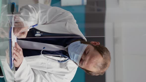 Vertical Video Doctor Taking Notes and Giving Prescription Paper to Female Patient