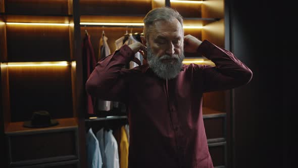 Stylish Bearded Mature Man Getting Ready in Morning Buttoning Up His Shirt in Dressing Room Empty