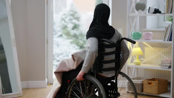 Disabled Young Woman in Hijab Rolling Wheelchair to Glass Door Indoors