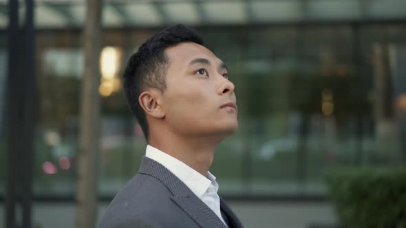 Real Time Portrait Shot of a Young Asian Businessman Walking Down the Street and Looking Around