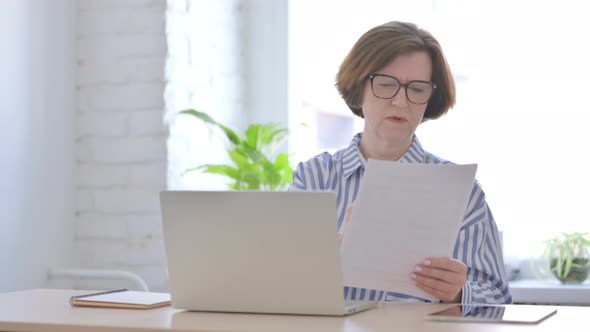 Senior Woman Upset While Reading Documents in Office