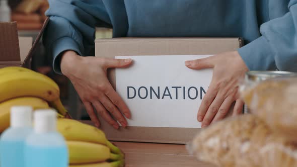 Close Up of Woman Sticking Paper with Word Donation on Box