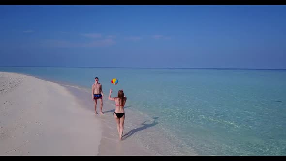 Romantic couple in love on idyllic coastline beach lifestyle by blue ocean and white sandy backgroun