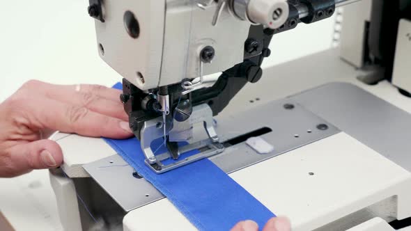 Female Worker Using a Sewing Machine To Cut Holes for Buttons