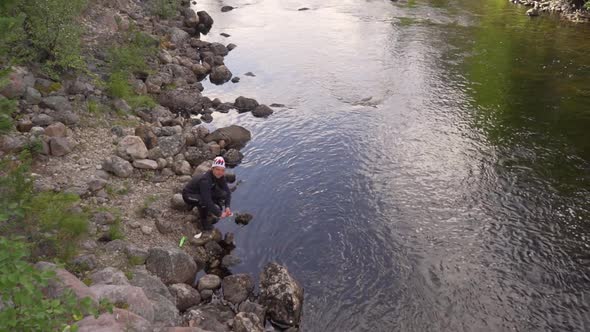 A man is washing the dishes in a river