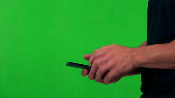 Young Man Works on Smartphone (Typing) - Green Screen - Studio - Closeup