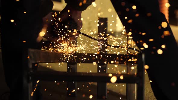 Worker's Hands Hold a Working Angle Grinder