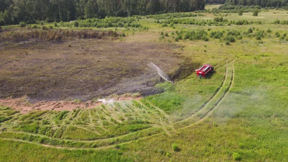 A Firefighter Pours Water From a Hose on the Edge of a Steaming Field