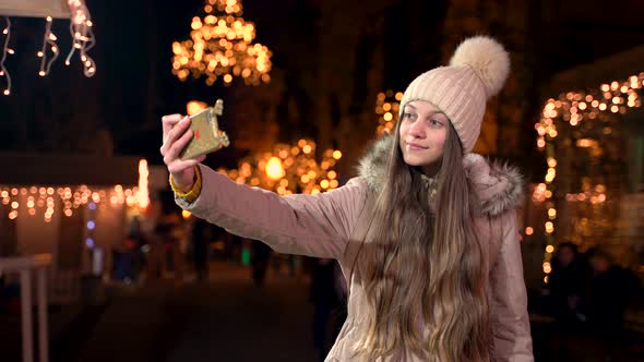 Beautiful teenager with long hair taking a selfie at Christmas market.