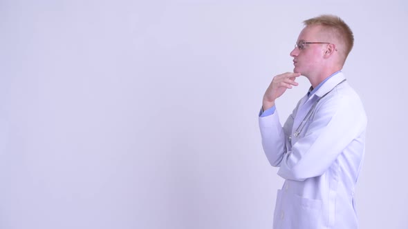 Profile View of Happy Young Blonde Man Doctor Thinking