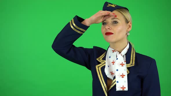 A Young Beautiful Stewardess Protects Her Eyes From the Sun and Looks Around - Green Screen Studio