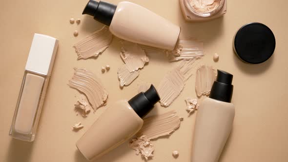 Bottles of Makeup Foundation and Samples on Beige Background