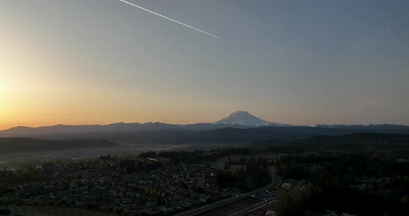 Aerial of a jet stream flying over Mount Rainier at sunrise.