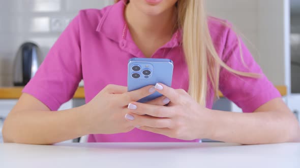 Blonde girl typing message on modern smartphone with triple camera in 4k video