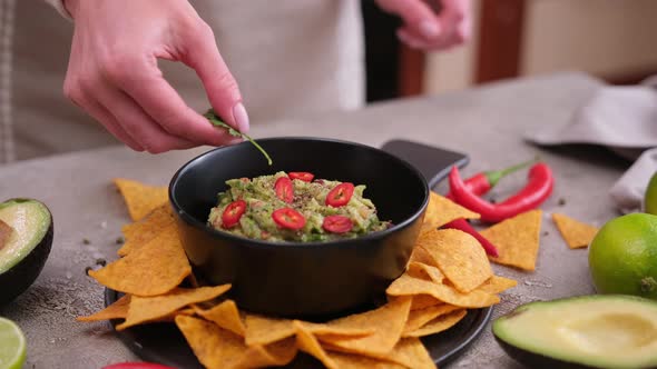 Woman Adding Pepper and Spices to Freshly Made Guacamole Dip Sauce in Marble Bowl Mortar