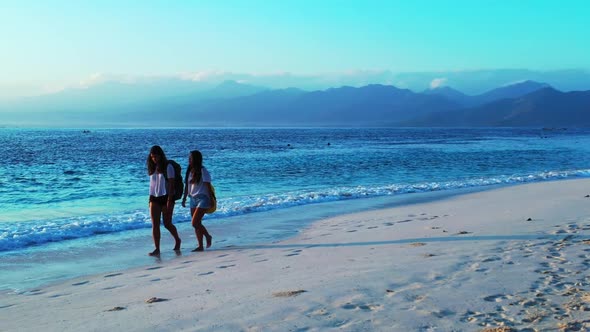 Women happy together on paradise lagoon beach journey by shallow lagoon with white sand background o