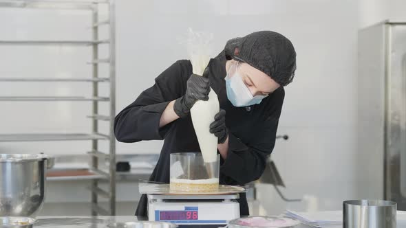 Portrait of Focused Female Confectioner Adding Layer on Baked Cake Dough Standing on Kitchen Scales