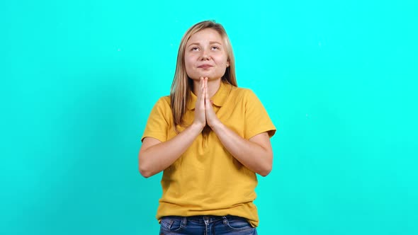 The Young Woman in Suspense with Her Hands Together Looks Up.