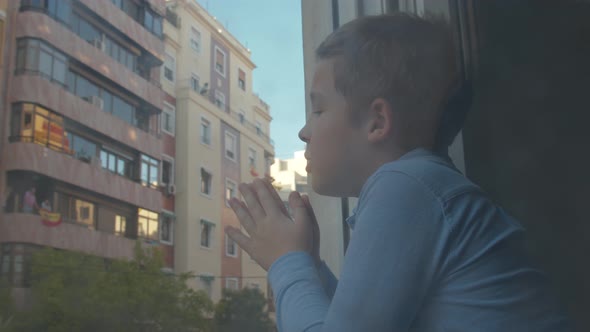 Child in quarantine applauding to doctors from open window. Coronavirus pandemic