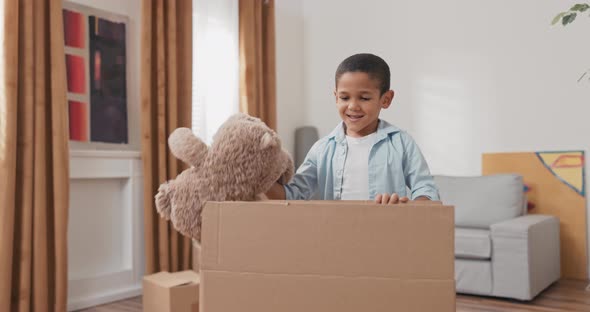 A Little Smiling Sweet Boy After Moving Into a New Apartment Searches Among the Boxes of His Toys