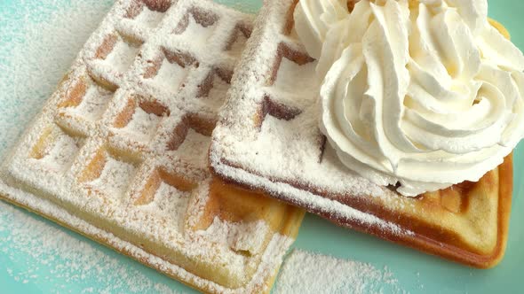 Preparation of waffles. Whipped cream is applied to the waffles.