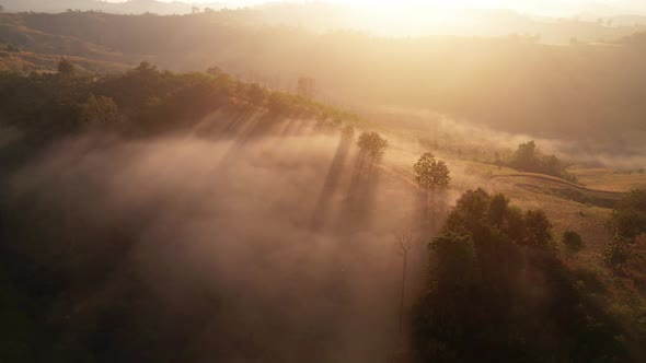 The rays of the sun shine through the clouds into the misty sea above the mountains in the morning