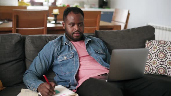 African man writing something from laptop