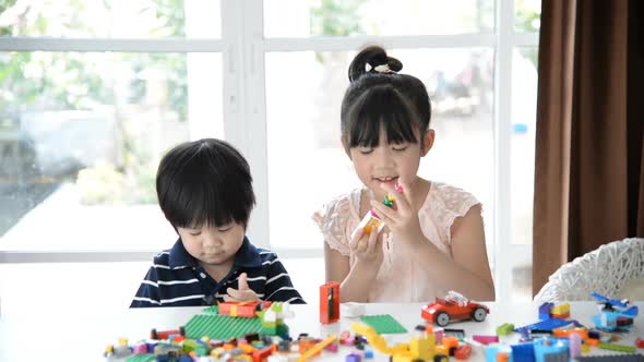 Little Asian Children  Playing With Colorful Construction Blocks On White Table