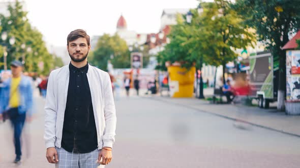 Time-lapse of Handsome Guy Towny Standing in the Street Downtown and Looking at Camera with People