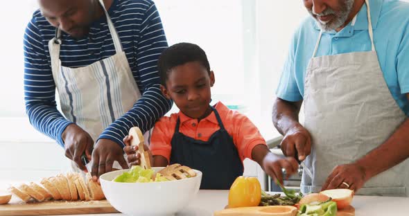 Boy preparing salad with his father and grandfather