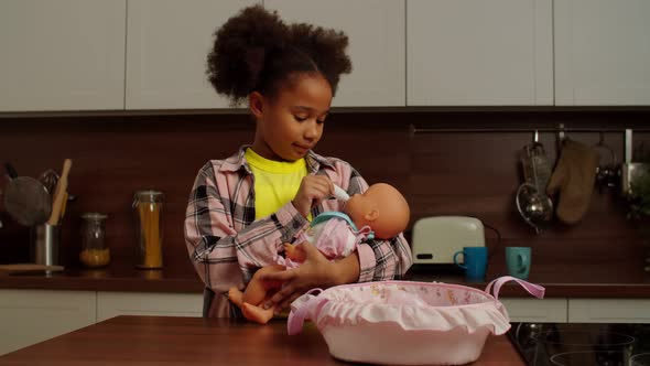 Cute School Age African American Girl Playing Mother with Doll Indoors