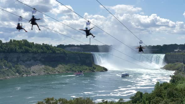 Zip line riders descending down by the Niagara Falls, summer adventure