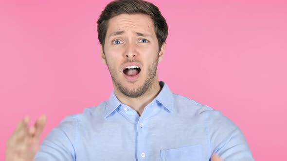 Young Man Upset by Failure on Pink Background