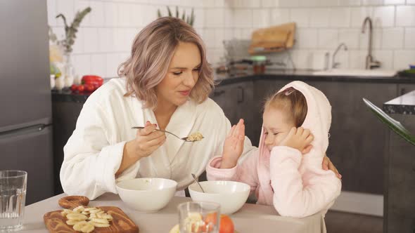 Beautiful Young Mother Tries To Feed Her Little Daughter Oatmeal Porridge Girl Refuses To Eat