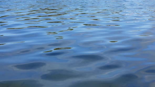 Ripples of blue clean river surface water up close. Background tranquil sequence. SLOW MOTION