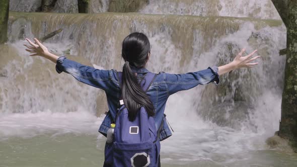 Young Woman Raised Arms Enjoying Life At Waterfall