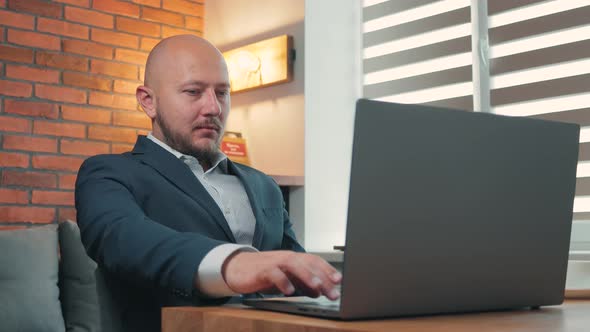 Portrait of young man in the suit working with laptop on wooden work desk at home office