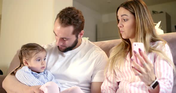 Happy Parents and Little Girl Are Resting at Living Room in Apartment, Chatting