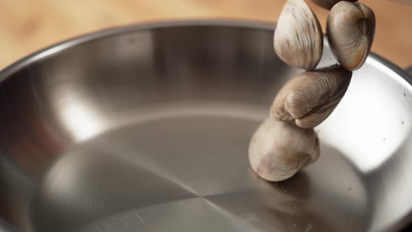 Camera follows cooking clams in a pan. Slow Motion.