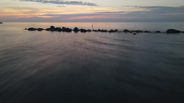 Lake Erie at sunset in Erie, Pennsylvania with low drone shot over water, breaker and buoy.