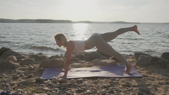 The Beautiful Athletic Woman Doing Morning Exercises on the Seashore. Beach and Sunrise on the