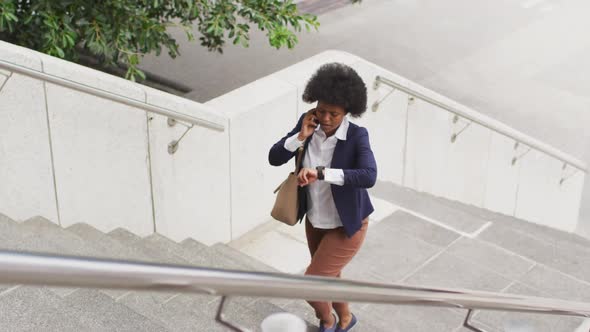African american businesswoman walking and talking on smartphone
