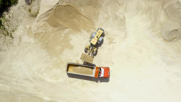 Bulldozer loading a truck with sand at sand extraction area, 